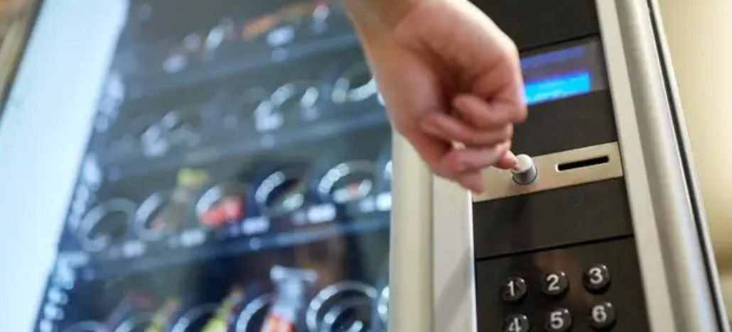 A hand pressing a selection button on an Evans Vending machine